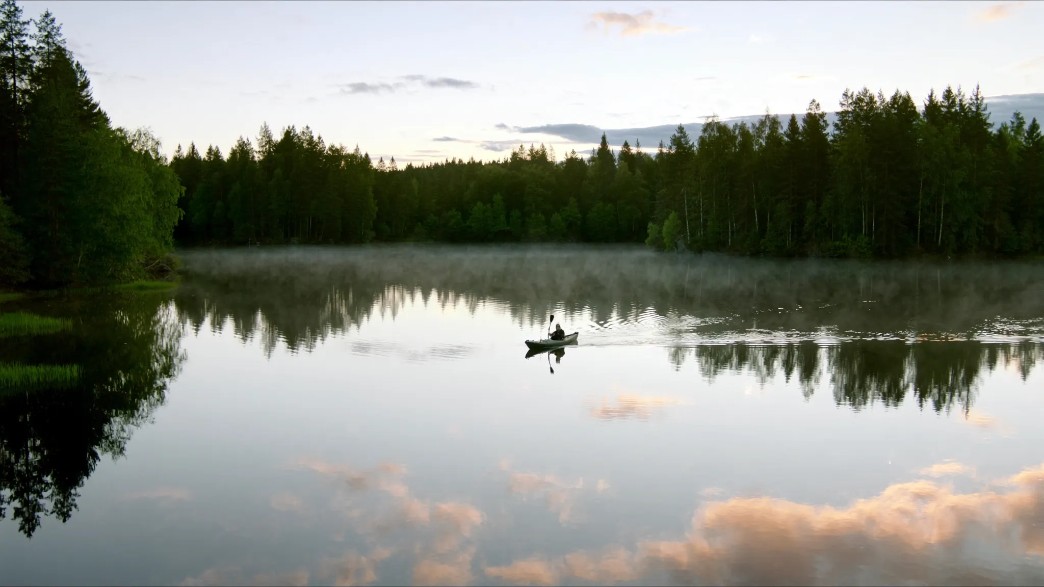 Kajak på spegelblank sjö i Värmland tidigt på morgonen